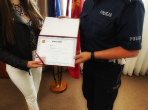 Dyplom przekazany 40-tysięcznej kierującej w powiecie grajewskim, w tle policjant i kobieta