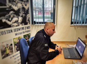 Policjant, siedzący przed komputerem, zajęcia online