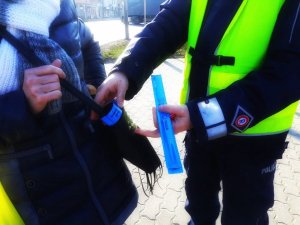 Policjant zakłada opaskę odblaskową kobiecie na torebkę damską