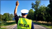 policjant ruchu drogowego z podniesioną ręką stoi na drodze
